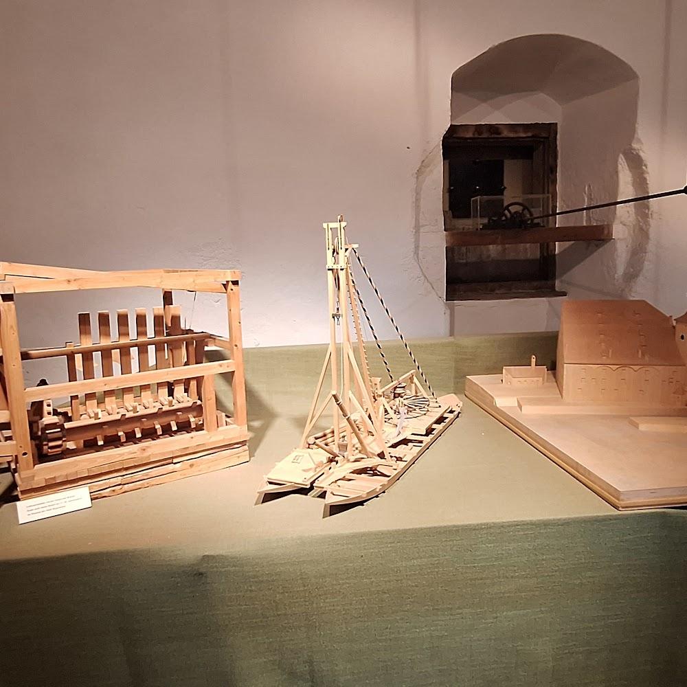 Wooden model ship, wooden model of a building, and a wooden model of a device.  The device looks like a waterwheel.  The model building may represent the landmark of the city of  Gdańsk.